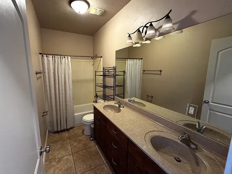Bathroom with shower/tub, toilet, and two sinks. Double cupboards and three drawers create space for substantial storage.