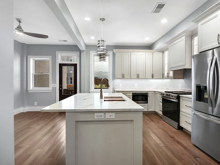 kitchen with L-shaped island and Quartz counters; appliances exterior door to yard