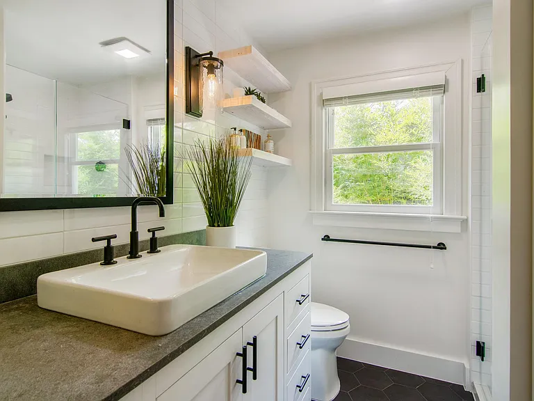 Guest Bathroom. Completely remodeled featuring large mirror, cabinetry, black tile flooring, concrete style granite countertops.