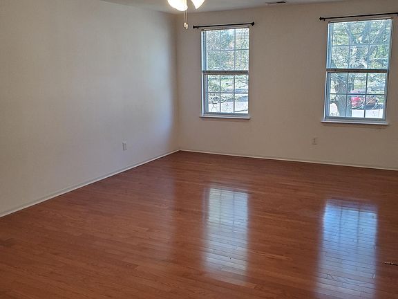 View of living room with hardwood floors toward front of property. Note central lighting and ceiling fan.