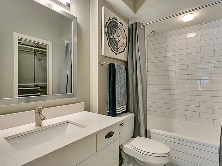 Beautiful modern white bathroom with white subway tiles, soaking tub, and framed mirror with white quartz countertop