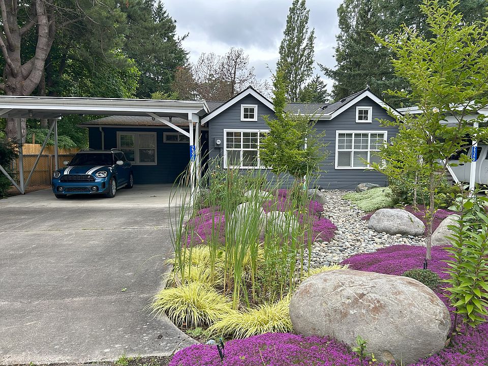 Front view of 2324 Soundview duplex on the left. Covered carport for two cars, plus driveway parking.