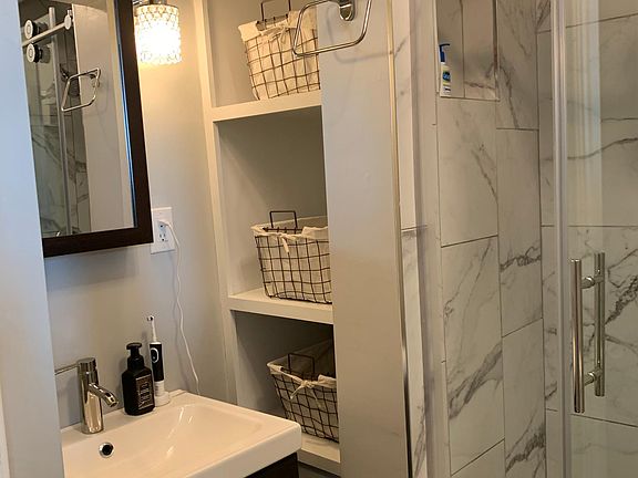 bathroom with walk-in shower, floating vanity, storage shelves