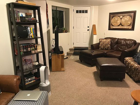 East half of living/dining area at night. Picture window looks out at front garden.