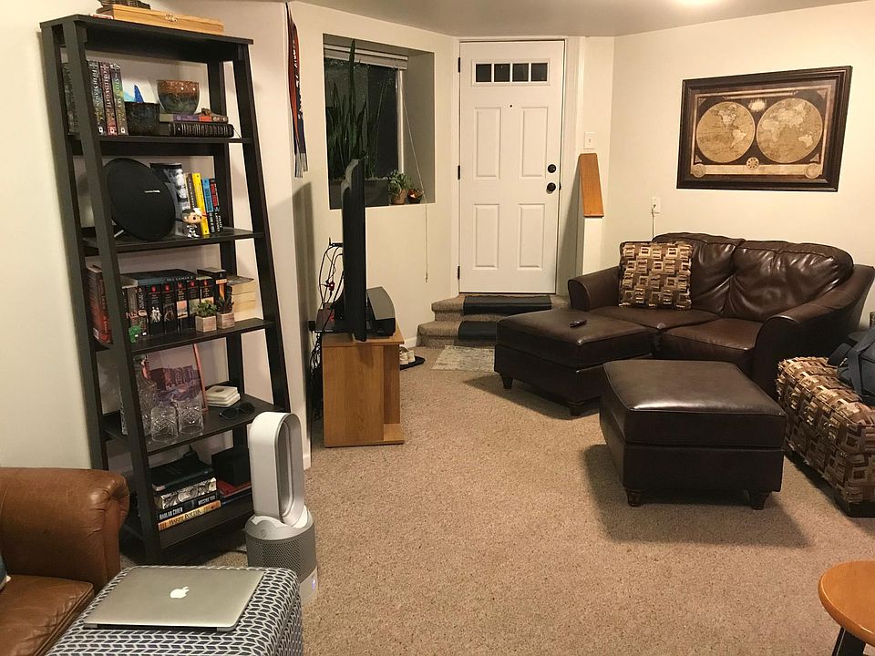 East half of living/dining area at night. Picture window looks out at front garden.