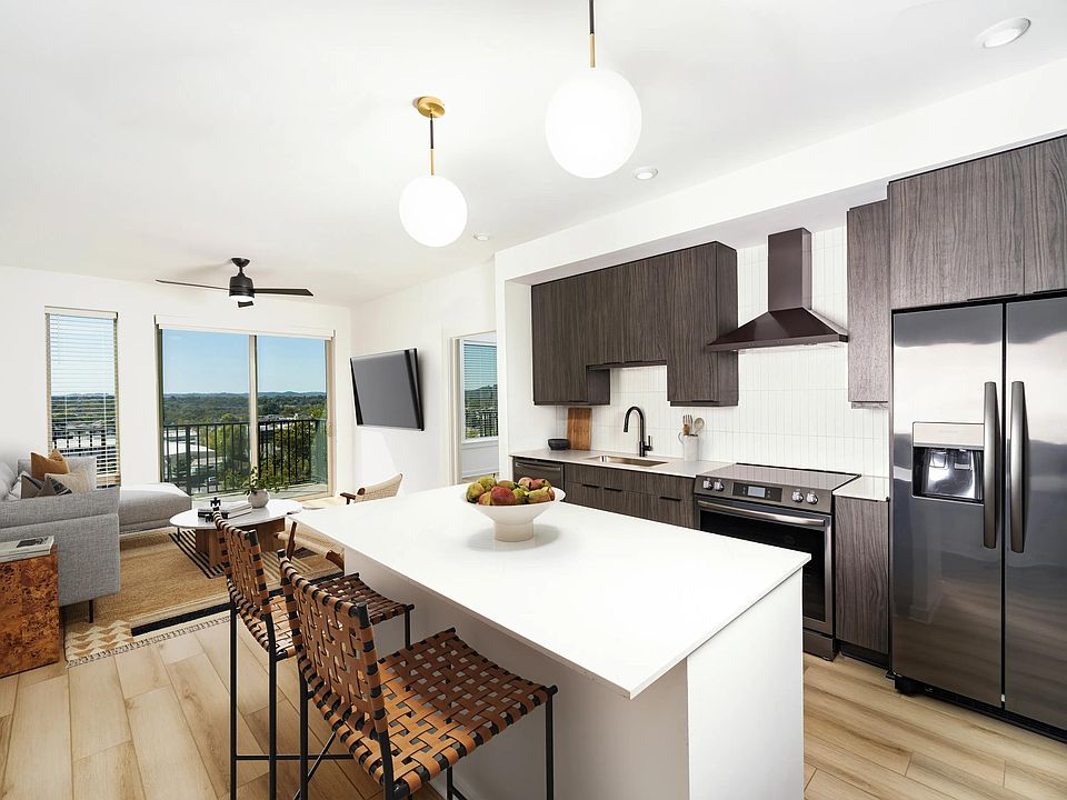 An open kitchen at Modera Nations in Nashville features a spacious island and the choice of light or dark finishes, with skyline views extending the living space.