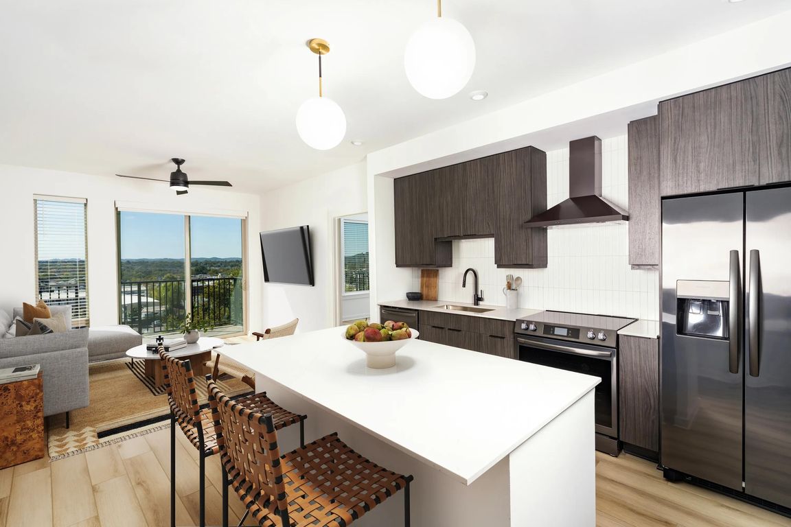 An open kitchen at Modera Nations in Nashville features a spacious island and the choice of light or dark finishes, with skyline views extending the living space.