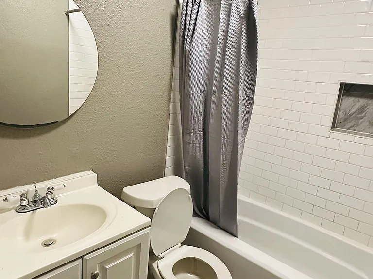 Full bathroom with a tub/shower combo, subway-tile surround, and vanity with sink plus a wall mirror for daily routines.