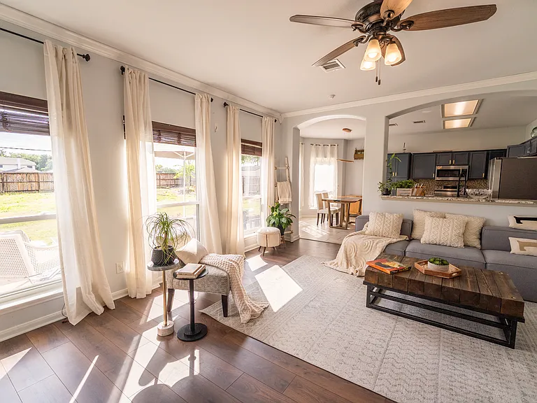 Sun-Drenched Living Space: Relax in a bright, airy living room framed by tall windows that let in an abundance of natural light. Cozy up in a beautifully styled layout that offers plenty of room for comfortable seating and media setups.