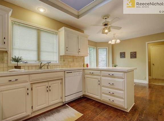 Light and bright eat-in kitchen with white cabinetry and hardwoo