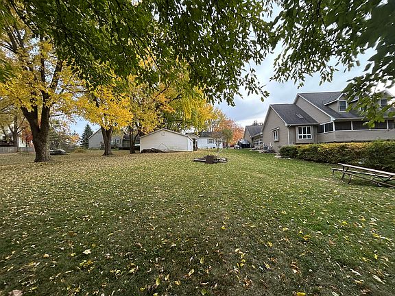 Large backyard with fire pit. The yard backs up to a green area with a dock for lake access