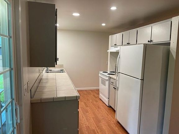 Galley style kitchen with tile countertops, Fridge, Stove/Oven, Microwave & Dishwasher.
