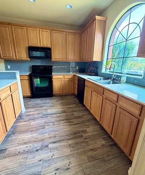 Spacious kitchen with full appliance suite, plenty of counter space for cooking, abundance cabinet storage, and an arched window overlooking the front yard