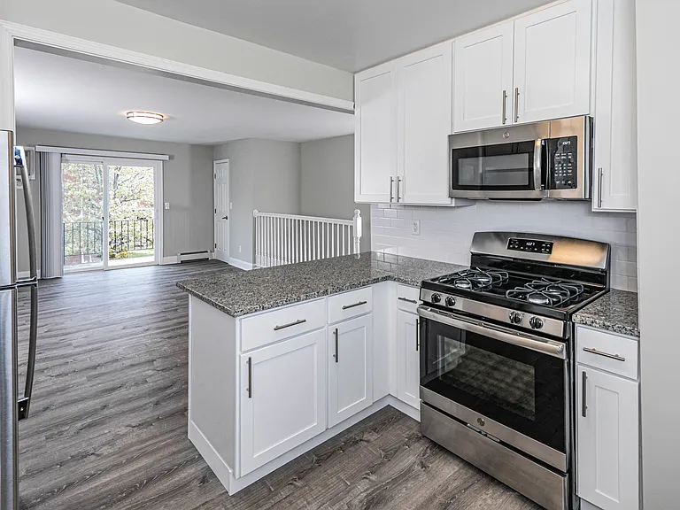 Newly renovated open kitchen featuring stainless steel appliances, granite counter tops and modern white cabinets.