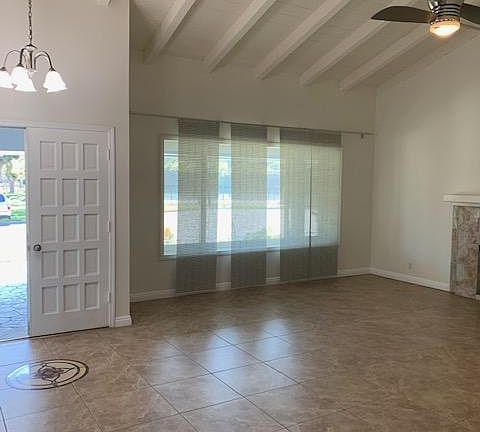 Double door entrance with decorative tile floor leads to bright living room with high beam ceilings.
