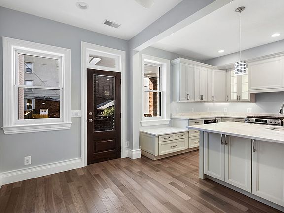 Dining area in front of island highlighting rear Marvin tilt windows with 3/4 view single lite exterior door leading to deck