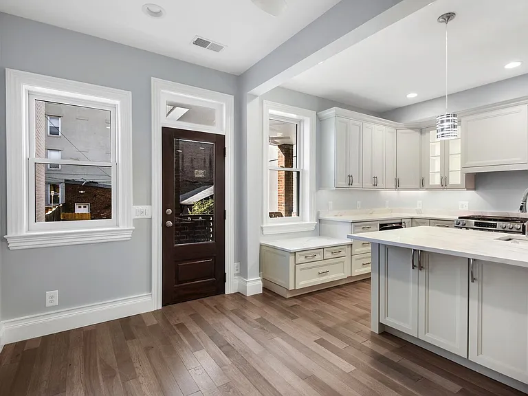 Dining area in front of island highlighting rear Marvin tilt windows with 3/4 view single lite exterior door leading to deck