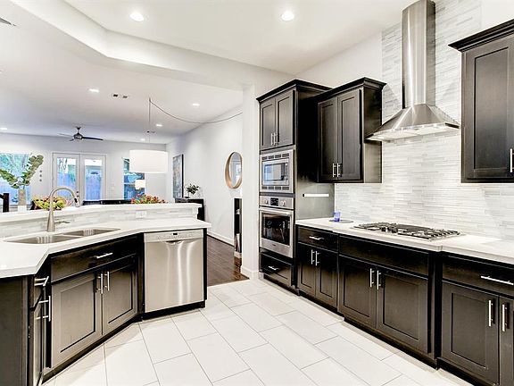 Look at this gleaming kitchen! Dark cabinets, stainless Bosch appliances, sleek quartz countertops, and a stylish vent hood.