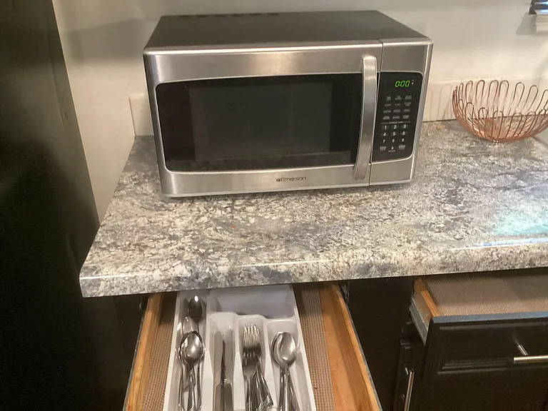 Kitchen countertop space with a microwave and convenient utensil drawer storage for everyday meal prep.