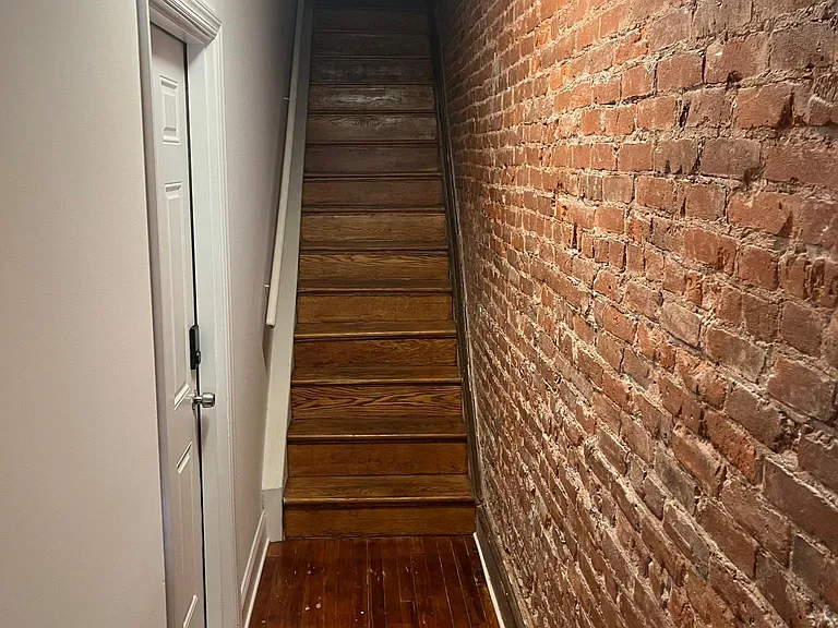 Exposed brick wall in hallway/staircase from first to second floor
