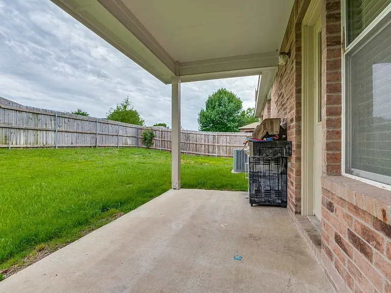 Covered patio overlooking enclosed backyard.