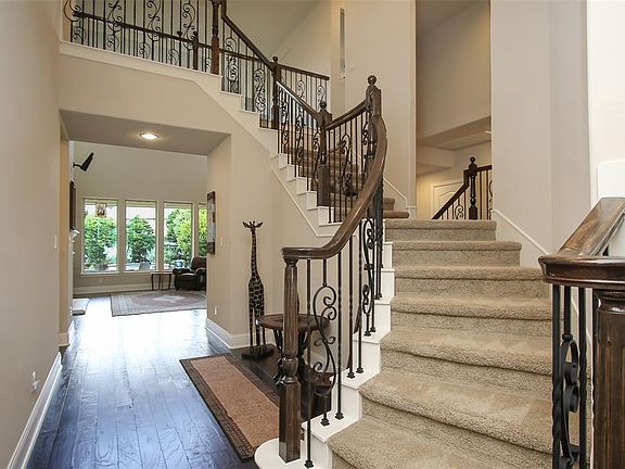 The entry way has double height ceilings and pretty ironwork on the staircase.