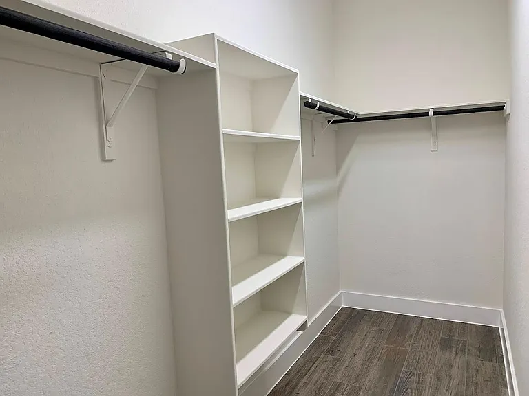 Primary bedroom has long walk in closet with built in storage.