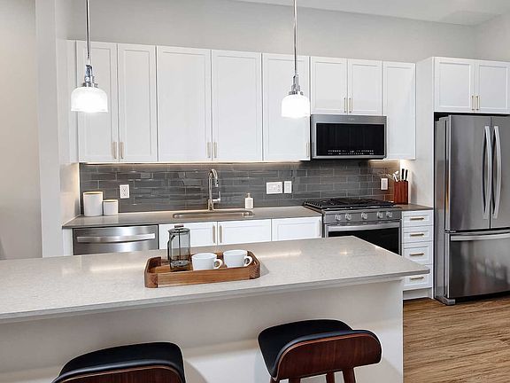 Classic Scheme kitchen with quartz countertops and island, stainless steel appliances, backsplash and hard surface flooring