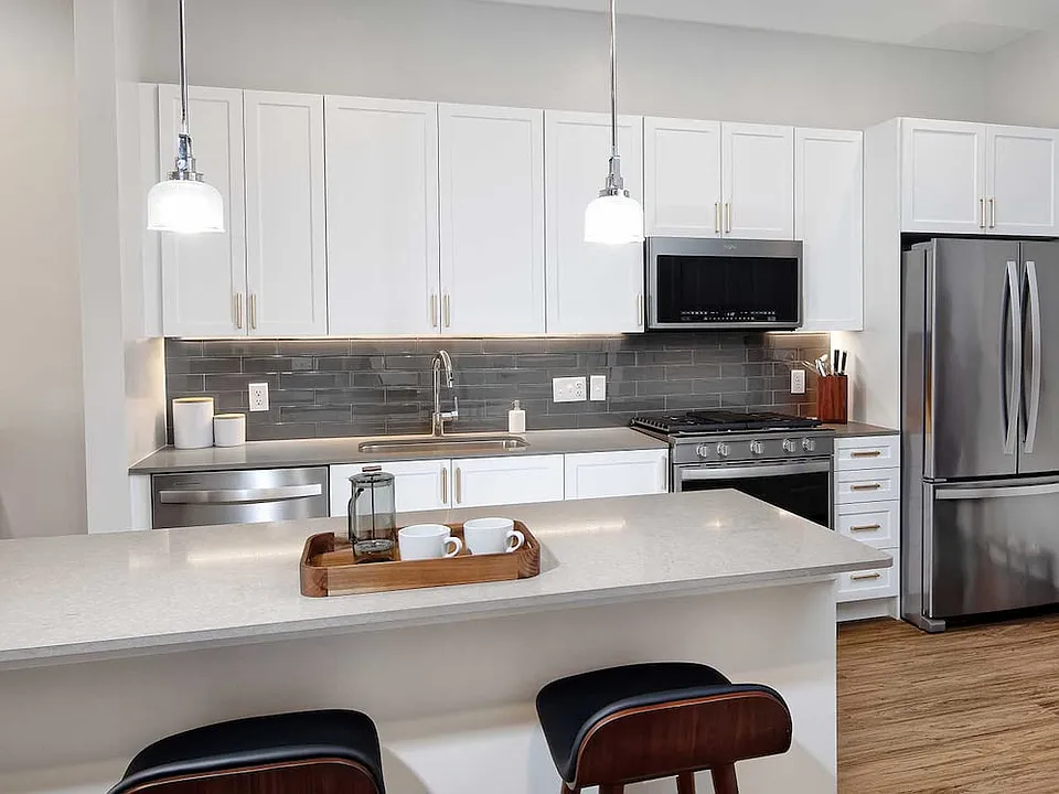 Classic Scheme kitchen with quartz countertops and island, stainless steel appliances, backsplash and hard surface flooring