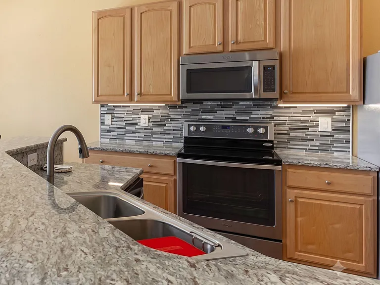 Well-appointed kitchen with ample wood cabinetry, granite-look counters, and stainless steel range with built-in microwave.