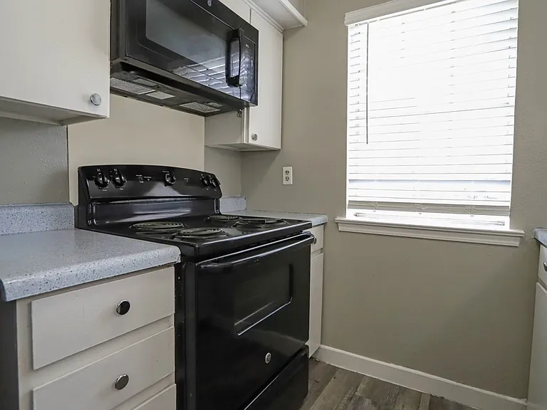 Fully equipped kitchen featuring black appliances, ample cabinet space, and window lighting.