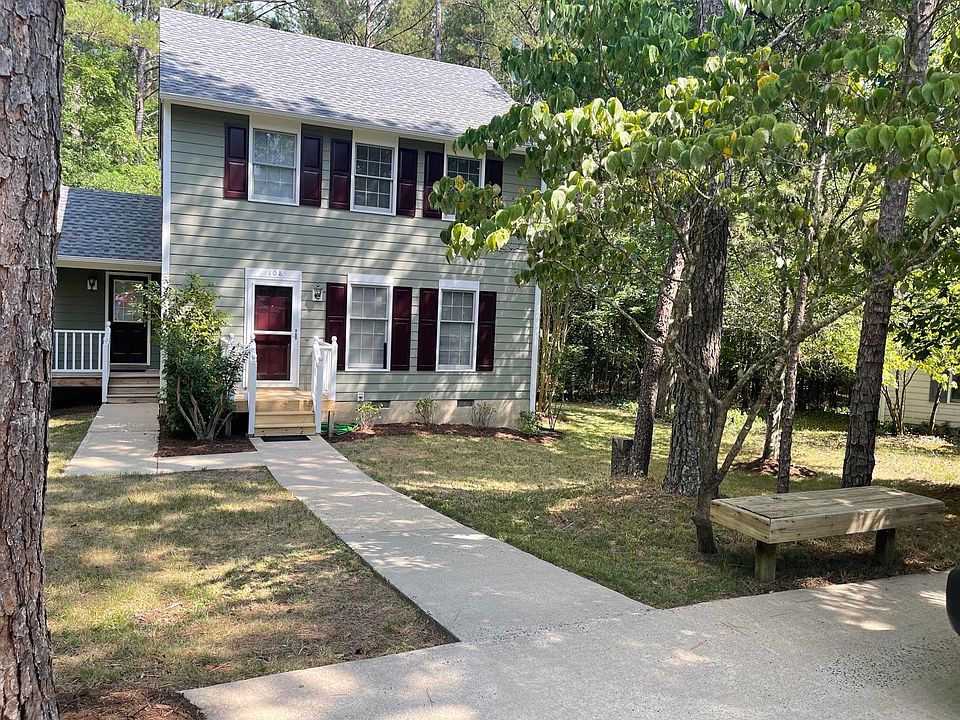 Front of house showing front and side porch. Note welcome bench at top of driveway.