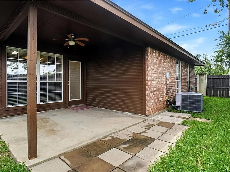 Covered concrete patio featuring a ceiling fan, brick exterior, and a sliding glass door