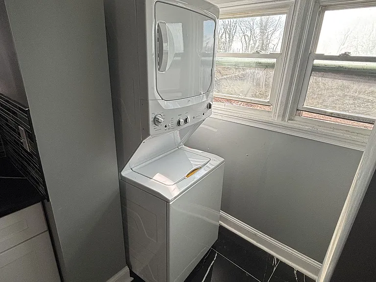 Convenient in-home laundry nook with a stacked washer/dryer and nearby windows for added ventilation and light.