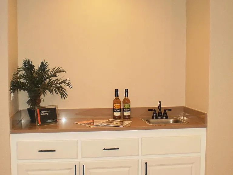Enjoy a cold drink at the Crimson layout with this bar and convenient sink and outlet to hook your wine cooler