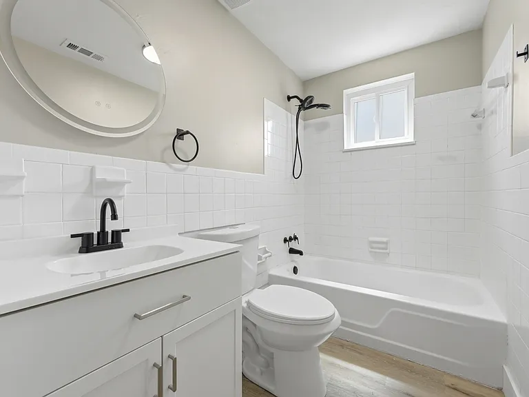 Renovated bathroom with new vanity, toilet, fixtures, fan, and LED mirror.