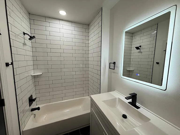 Modern bathroom with LED vanity mirror and Bluetooth speaker in ceiling.