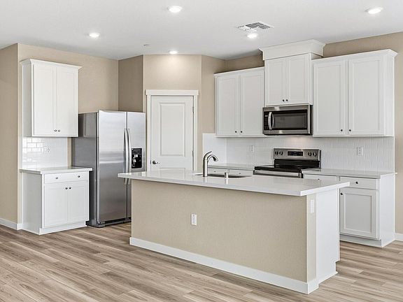 The kitchen has stainless steel appliances and plank flooring.