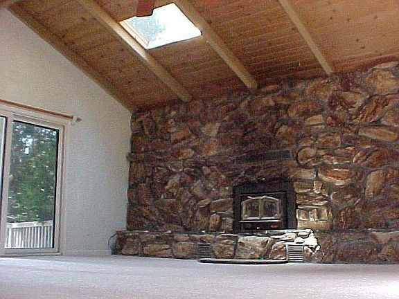 Living room stone fireplace with skylights and ceiling fan for memories