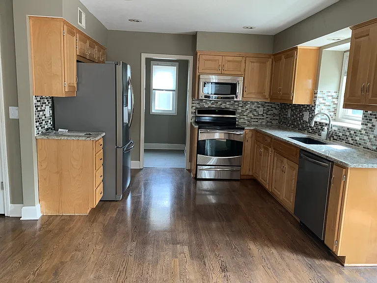 Updated kitchen with stainless steel appliances, ample cabinetry, hardwood flooring, and functional open layout.