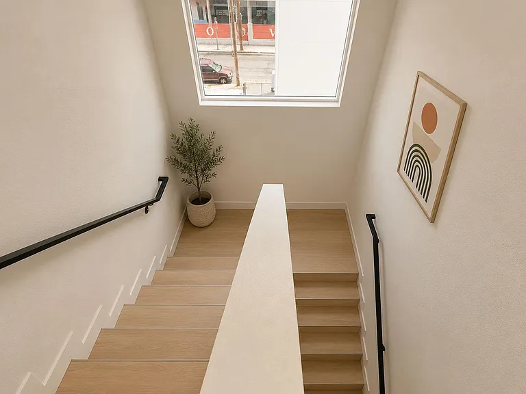 Clean stairwell with modern railings, light wood steps, and a large window bringing in natural light.