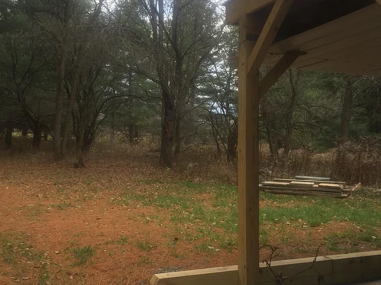 view of private yard from stone patio with deck above.
