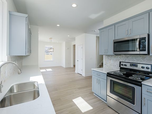 Custom kitchen with stainless steel appliances, quartz countertops and backsplash