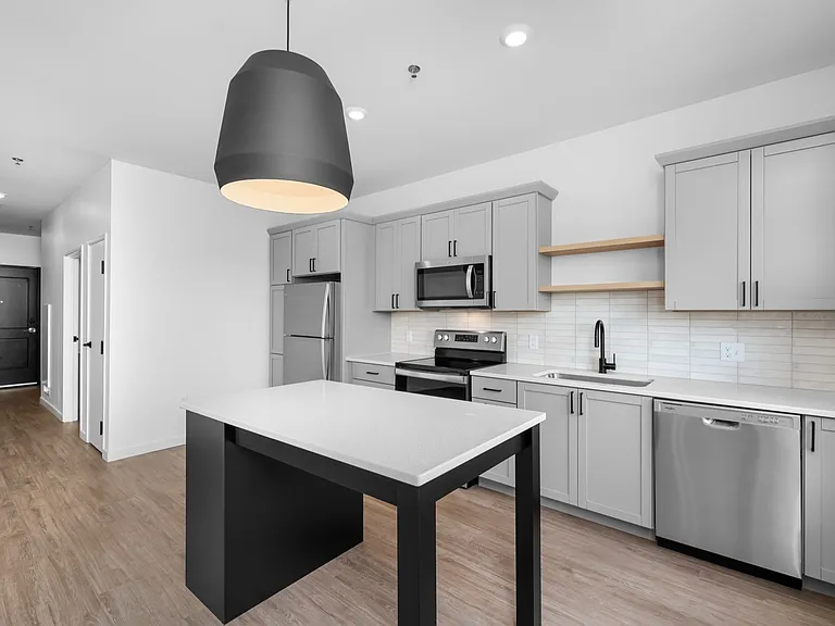 Modern kitchen with sleek gray cabinetry, stainless steel appliances, and a stylish pendant light over a central island. Modern kitchen with sleek gray cabinetry, stainless steel appliances, and a stylish pendant light over a central island.