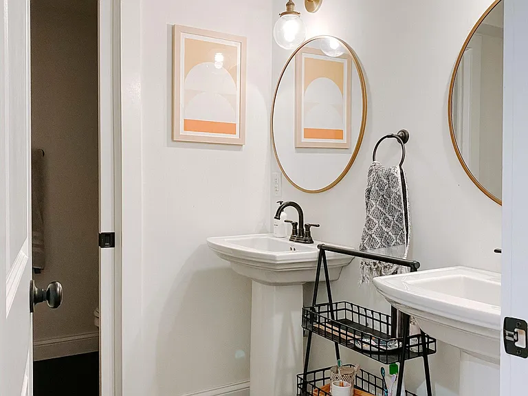bathroom w/ two sinks + pocket door between sink area and shower/toilet area