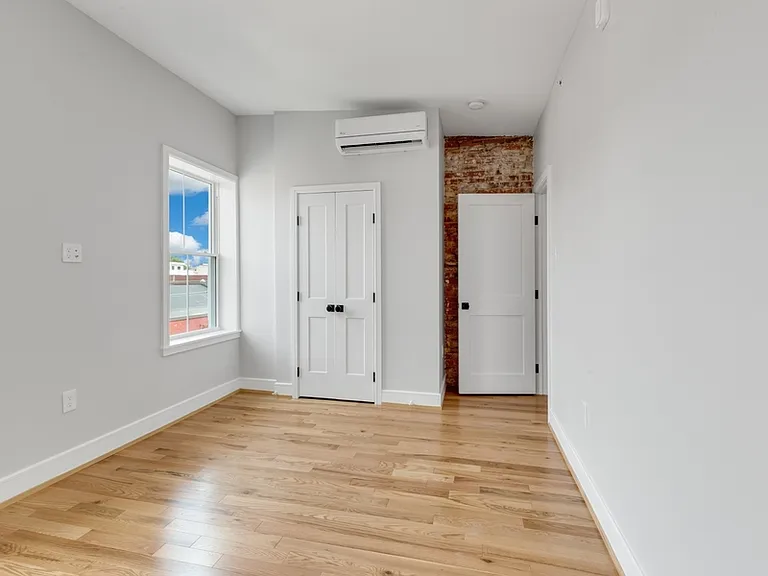 The larger bedroom has two large windows and a storage closet.