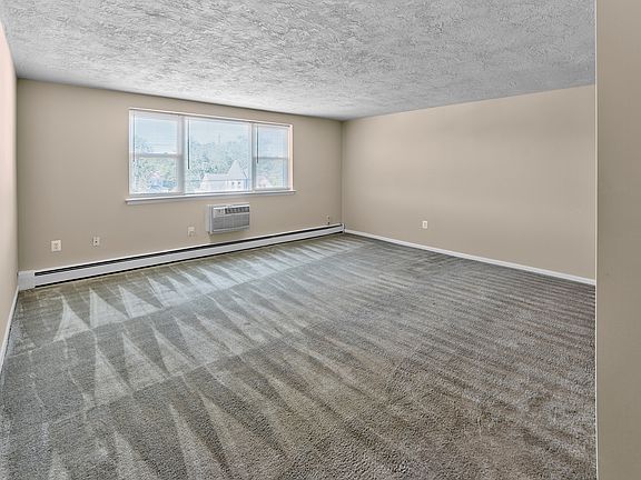 Enjoy open-concept living with a spacious carpeted living area at Audubon Arms Apartments.