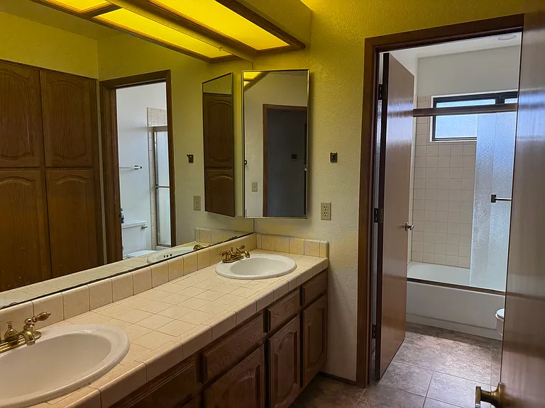 2nd bathroom upstairs with dual vanity, cabinet storage and separate toilet and bath/shower combo.