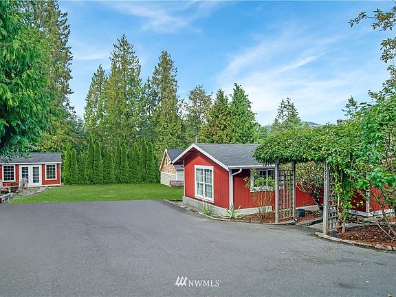 Adorable farmhouse with covered front porch on spacious lot surrounded by evergreens.  