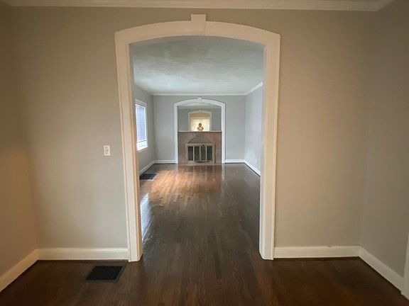 View from dining room into large living room with marble surround fireplace. Note the beautiful hardwood floors, lovely molding and high ceilings